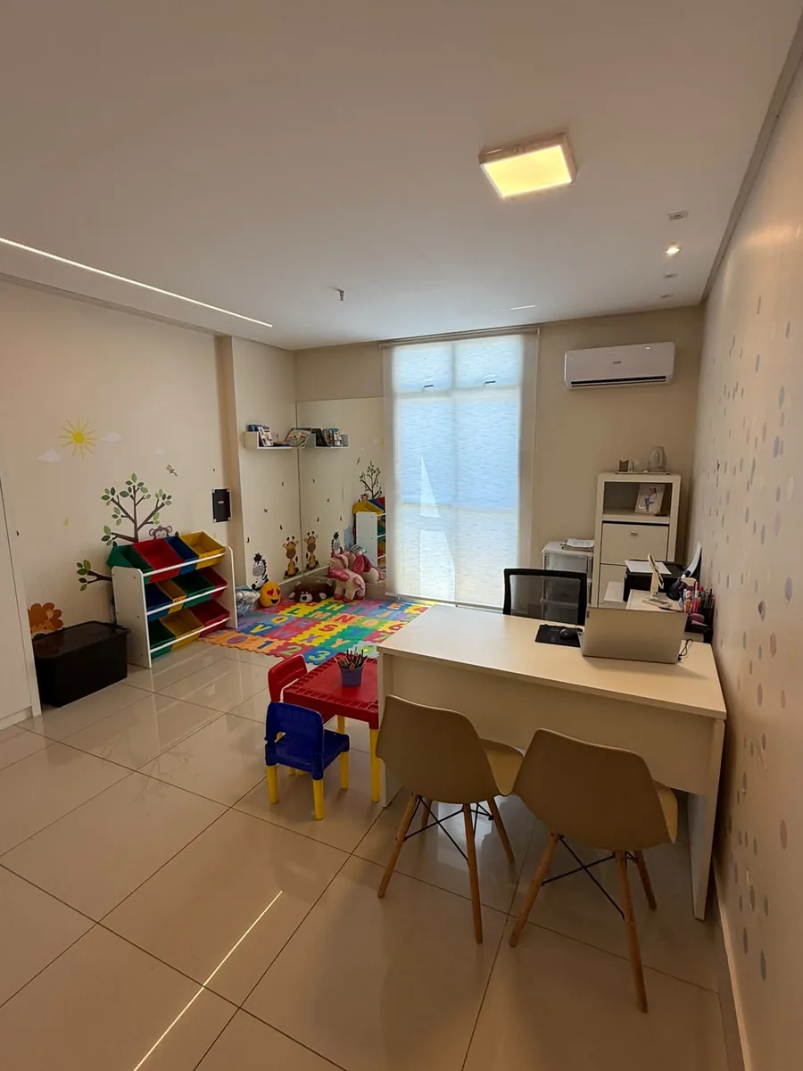 Sala infantil, com tapete de letras, mesinha colorida e adesivos de árvore na parede